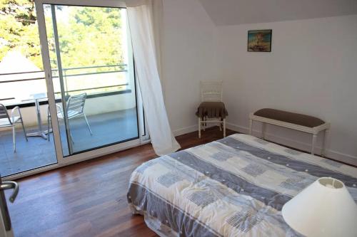 a bedroom with a bed and a balcony with a table at Maison "TY CASTERO" in Quiberon