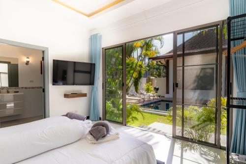 a bedroom with a white bed and a large window at villa Akala in Ban Saiyuan (1)