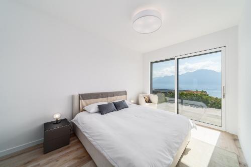 a white bedroom with a bed and a large window at Modern 5-Star Stay in Glion - Underfloor Heating in Montreux