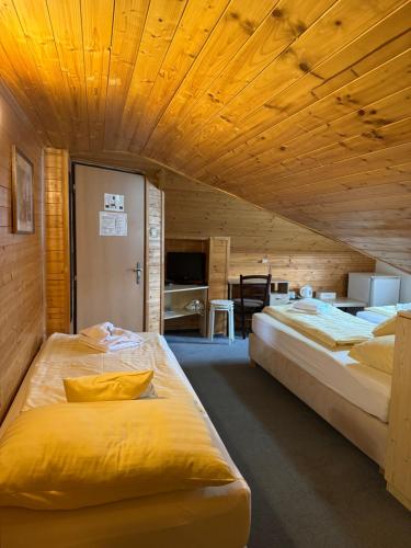 two beds in a room with wooden ceilings at Hostinec v Zátoce in Horní Těrlicko