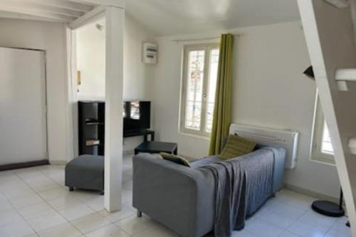 a living room with a couch and a chair at Duplex Mezzanine au calme Place de l'Horloge in Avignon