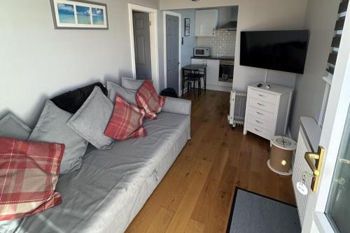 a living room with a gray couch with red pillows at Modern One Bedroom Chalet with Central Heating in Bridlington