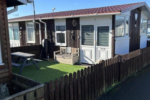 einen Zaun vor einem Haus mit einer Bank in der Unterkunft Modern One Bedroom Chalet with Central Heating in Bridlington