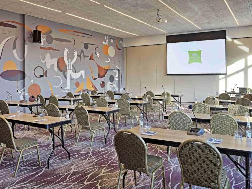 a conference room with tables and chairs and a projection screen at ibis Styles Sarajevo in Sarajevo