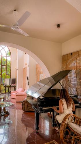 a woman sitting at a piano in a living room at Aeraki palms in Bordi