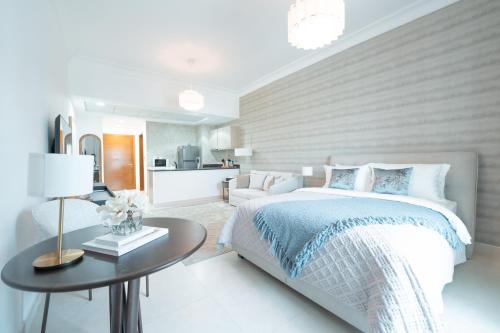 a white bedroom with a bed and a table at Modern Studio Living by Voyage in Abu Dhabi
