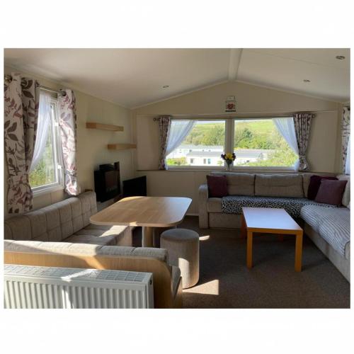 a living room with a couch and a table at Caravan - sleeps 6 & parking in Hollington