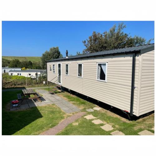 a white tiny house with a picnic table and a bench at Caravan - sleeps 6 & parking in Hollington