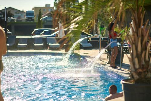a woman standing next to a pool with a fountain at Apartament Horizon by Alz in Mamaia Sat/Năvodari