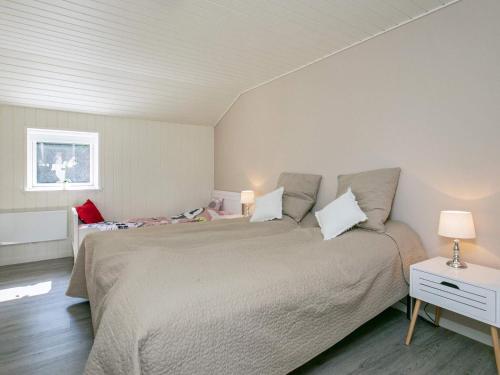 a bedroom with a large bed and a table with a lamp at 8 person holiday home in Væggerløse in Marielyst