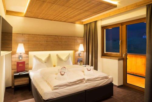 a bedroom with a large white bed with a window at Alpinhotel Berghaus spa in Tux