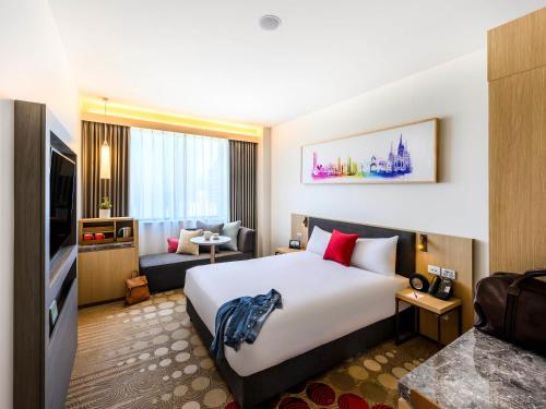 a hotel room with a large bed and a living room at ibis Melbourne Central in Melbourne