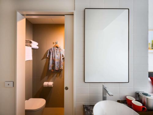 a bathroom with a toilet and a mirror at ibis Melbourne Central in Melbourne