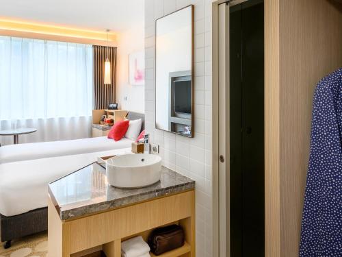a hotel room with a sink and a bed at ibis Melbourne Central in Melbourne