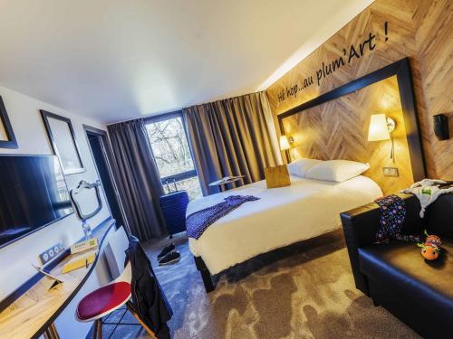 a hotel room with a large bed and a couch at ibis Styles Douai Gare Gayant Expo in Douai