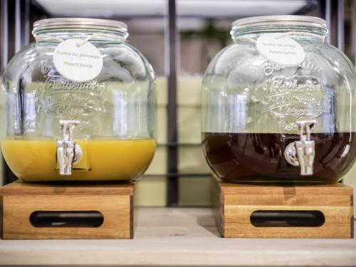 two glass jars filled with orange juice on a table at Ibis Styles Lisboa Centro Marquês de Pombal in Lisbon