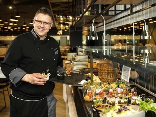 a man standing in a restaurant with a tray of food at ibis Budapest Castle Hill in Budapest