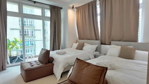 a bedroom with two beds and a chair and a window at Kuching City Riverine Diamond by Bed and Brew Staycation in Kuching