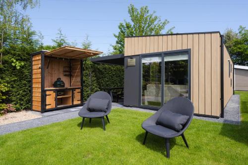 a tiny house with two chairs in the grass at Lodges van Rongen in Heinkensand