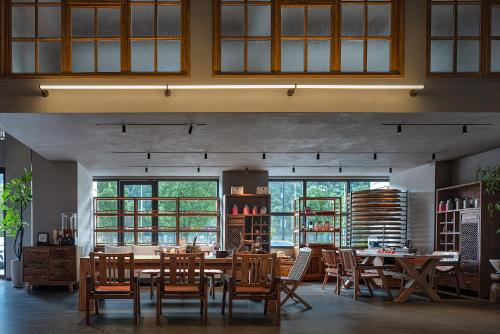 a dining room with tables and chairs and windows at Zhangjiajie SANHE Hotel --Free one way pick up service over 2 night, Free shuttle to east gate of forest park,Free laundry service,Free fresh coffee,English speaking customer service in Zhangjiajie