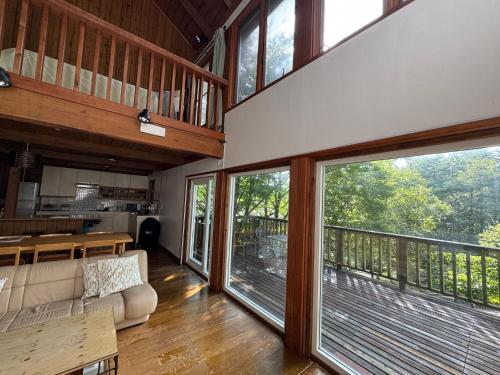 a living room with sliding glass doors and a balcony at Cabin A MtFuji view, BBQ, lake Saiko 3mins, hammock, wood deck in Narusawa
