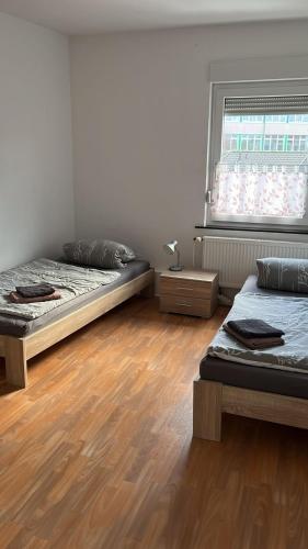 two beds in a room with wooden floors and a window at FeWo Neuenkirchen in Neuenkirchen