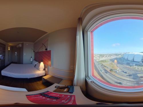 a room with a bed and a large window at ibis Natal in Natal