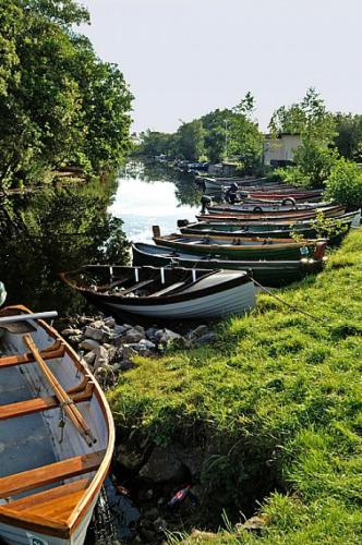 a row of boats lined up on the side of a river at 2 Bed in Oughterard oc-i492 in Porridgetown