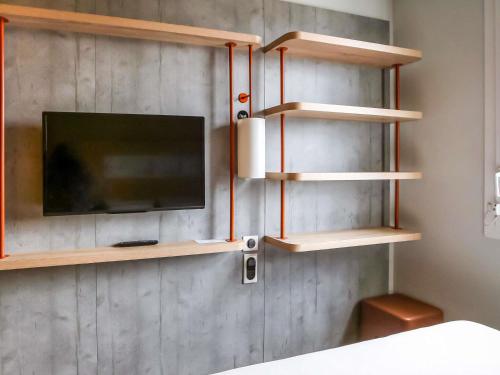 a room with wooden shelves and a tv on a wall at ibis budget Geneve Saint Genis Pouilly in Saint-Genis-Pouilly