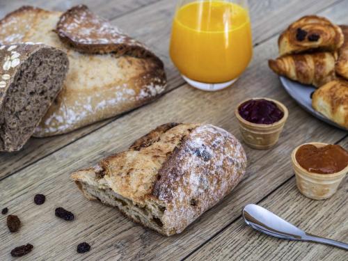 a table with bread and a glass of orange juice at Hôtel ibis Styles Montargis Arboria in Pannes