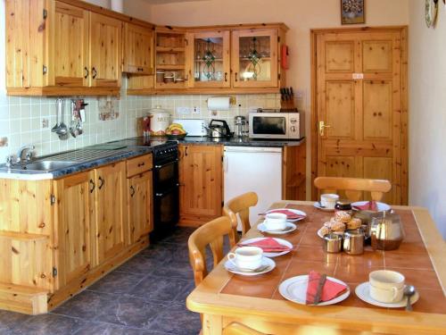 a kitchen with a wooden table with chairs and a tableablish at 2 Bed in Glengariff oc-ii03911 in Coomhola Bridge