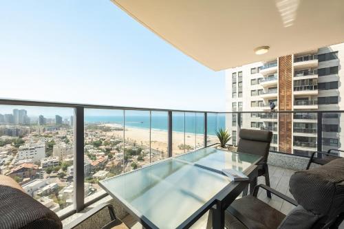 アシュドッドにあるThe Beach Tower Residenceのバルコニー(ガラスのテーブルと椅子付)、ビーチが備わります。