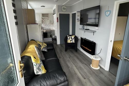 a living room with a black leather couch and a television at Cozy Seaside Chalet in Bridlington in Bridlington