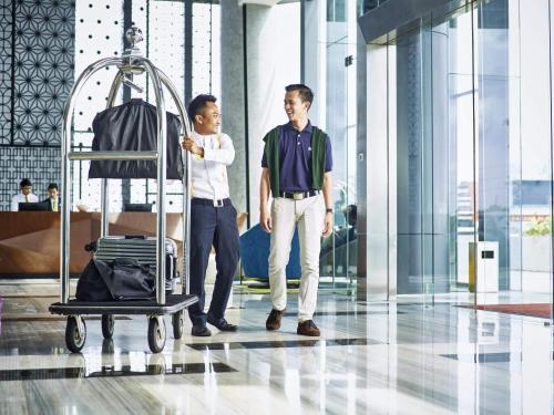 two men standing in an airport with a luggage cart at Novotel Karawang in Karawang