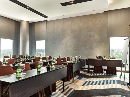 a restaurant with tables and chairs and large windows at Novotel Karawang in Karawang