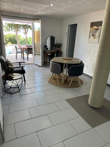 a living room with a table and chairs on a tile floor at Appartement deux chambres spacieux avec jardin et entièrement privatif dans lotissement très calme in Biguglia