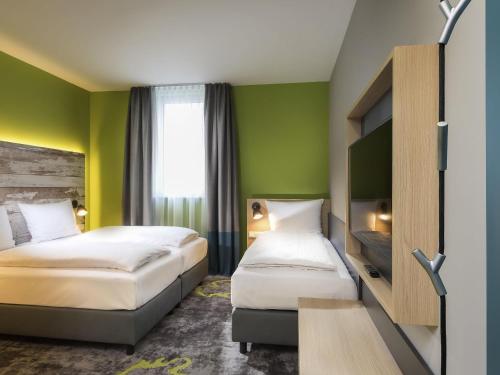 two beds in a hotel room with green walls at ibis Styles Stuttgart Vaihingen in Stuttgart