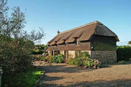 an old barn with a thatched roof and some flowers at 4 Bed in Carne oc-i023 in Carne