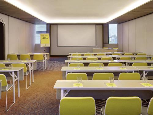 a classroom with tables and chairs and a whiteboard at ibis Styles Jakarta Tanah Abang in Jakarta