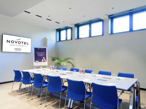 a conference room with a long table and blue chairs at Novotel Parma Centro in Parma