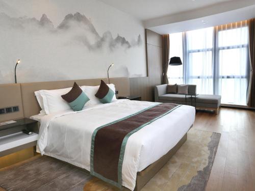 a hotel room with a large bed and a chair at Novotel Deqing Moganshan in Deqing