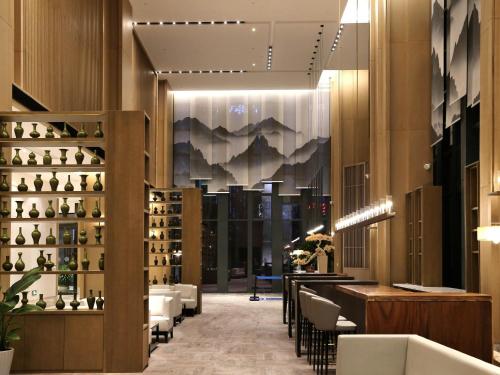 a lobby of a hotel with a bar and chairs at Novotel Deqing Moganshan in Deqing