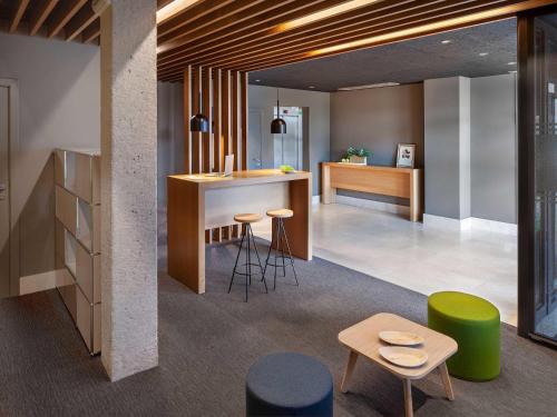 a lobby with a bar with stools and tables at ibis Styles Pamplona Noain in Noáin