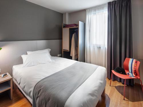 a bedroom with a large white bed and a window at ibis Styles Pamplona Noain in Noáin
