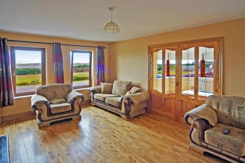 a living room with two chairs and a couch and windows at 4 Bed in Inch oc-i190 in Inch