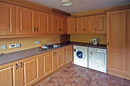 a kitchen with wooden cabinets and a washing machine at 4 Bed in Inch oc-i190 in Inch