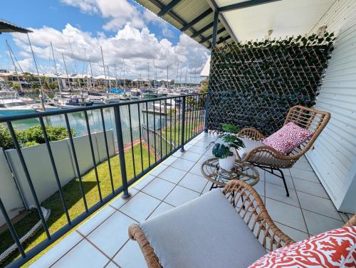 a balcony with chairs and a table and a view of a harbor at Marina Views Cozy 3br Villa In Tipperary Waters in Stuart Park