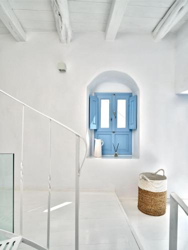 a white room with a blue door and stairs at Brunella Paros in Naousa