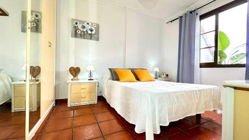 Un dormitorio con una cama con almohadas naranjas y una ventana. en Apartamento Terraza Los Realejos, en Los Realejos