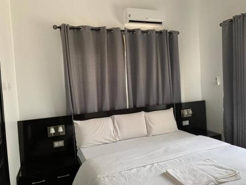 a bed with a black headboard and gray curtains at 3 Bed Apartment at a central location in Sango